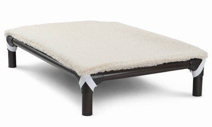 Cream color fleece accessory pad shown on top of a pvc bed, the pad is held to the bed by elastic straps that hook each the legs of the bed